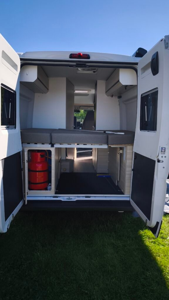 Obrázek interiéru obytného auta s pohodlnými sedacími plochami a úložným prostorem. Ideální pro kempování.