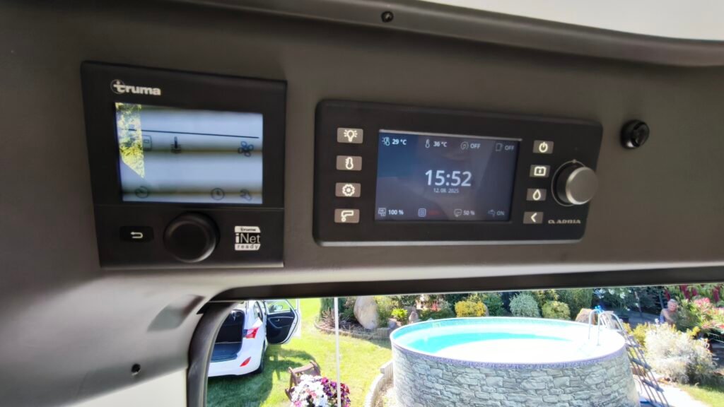 Obrázek interiéru obytného auta s ovládacími panely Truma. Komfortní nastavení teploty a osvětlení.