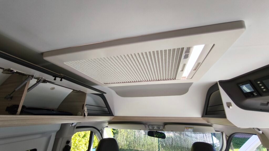 Obrázek interiéru obytného auta s moderním stropem a osvětlením. Komfortní a praktické řešení pro cestování.