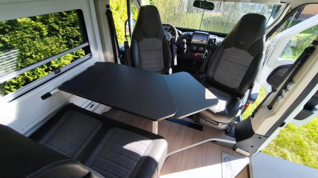 Obytné auto s moderním interiérem a praktickým stolem, ideální pro pohodlné cestování.