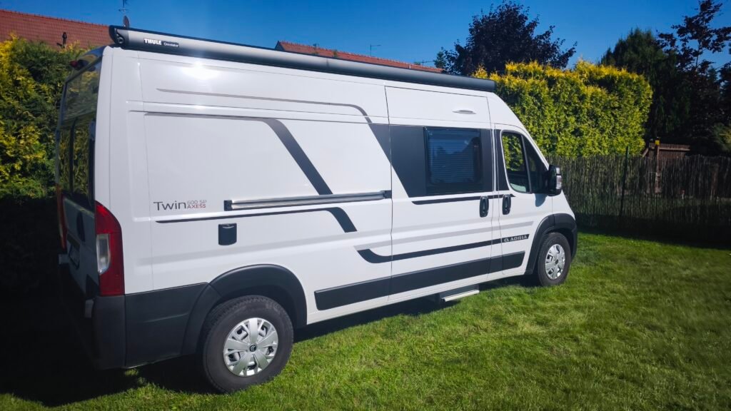 Obytné auto Adria Twin 600 SP AXESS na trávníku, ideální pro pohodlné cestování a kempování.
