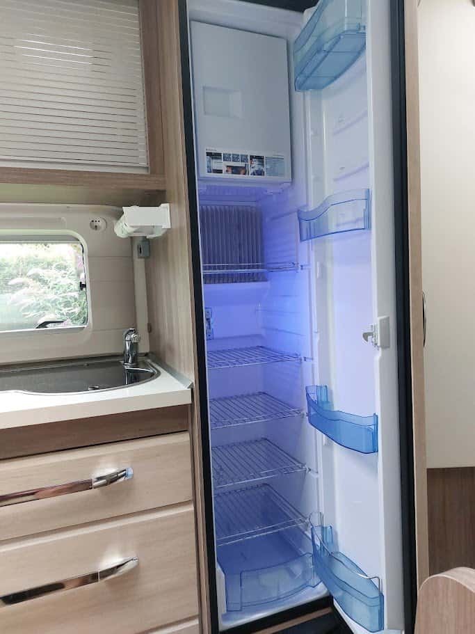 Obrázek ukazuje moderní chladničku v obytném autě s příjemným osvětlením a funkčním designem.