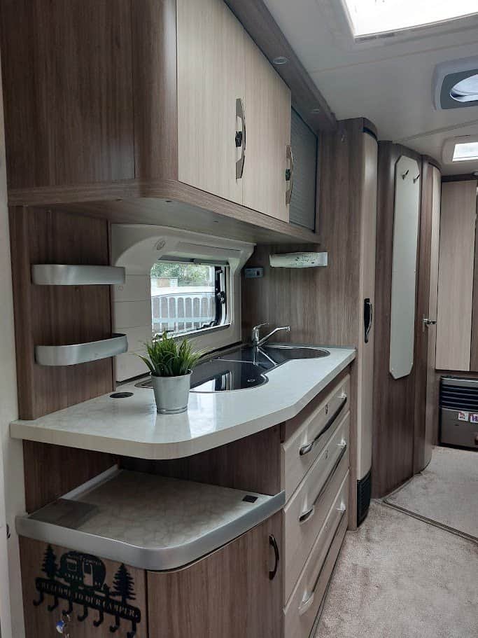 Moderní karavan s kuchyňským koutem a prostorově úsporným designem. Ideální pro pohodlné cestování.