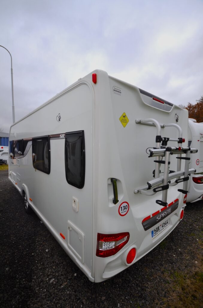 Karavan Sprite se střešním nosičem a velikými okny, ideální pro vaše dobrodružství.