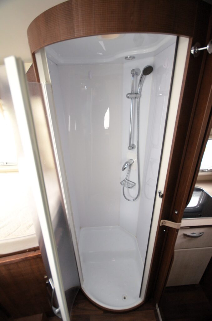 Obrázek znázorňuje sprchový kout v obytném autě. Moderní design a praktické uspořádání pro pohodlí cestovatelů.