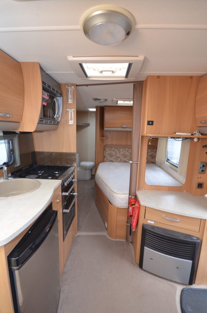 Interiér obytného auta s kuchyní, ložnicí a koupelnou. Moderní a funkční design pro pohodlné cestování.