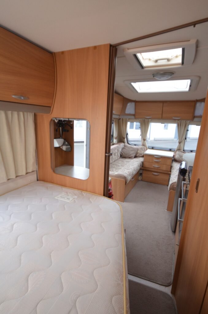 Interiér obytného vozu s pohodlným místem na spaní a útulným designem. Ideální pro dobrodružství.