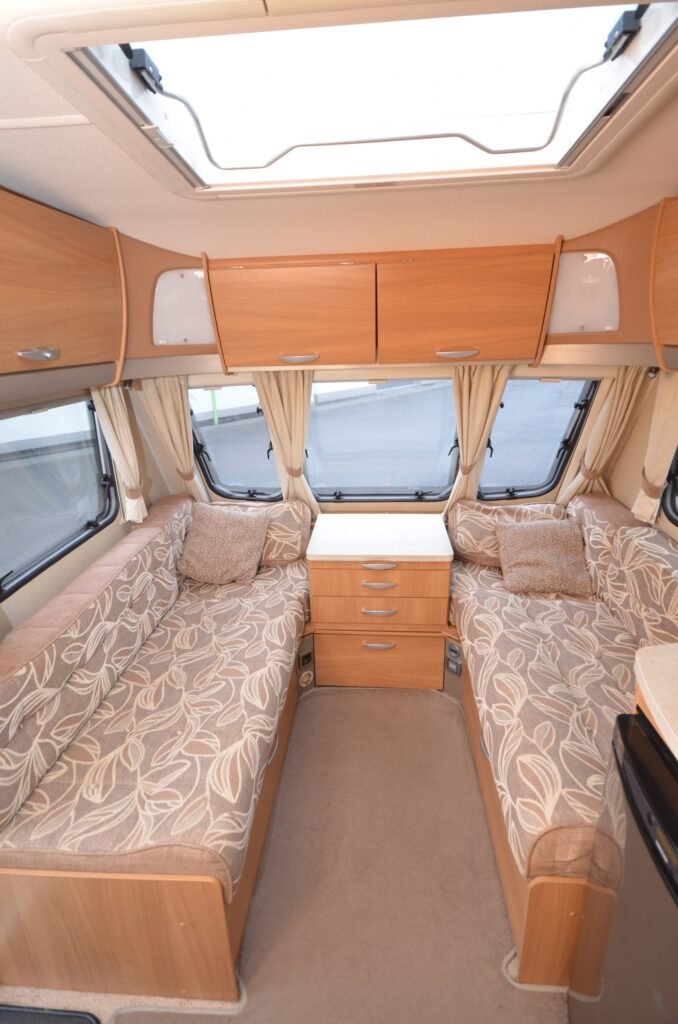 Moderní karavan s prostorným interiérem, dřevěným nábytkem a pohodlnými sedačkami. Ideální na cestování!