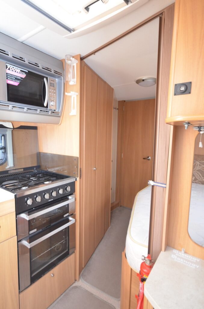 Obrázek interiéru obytného vozu s plně vybavenou kuchyní a útulným prostorem. Ideální pro cestování!