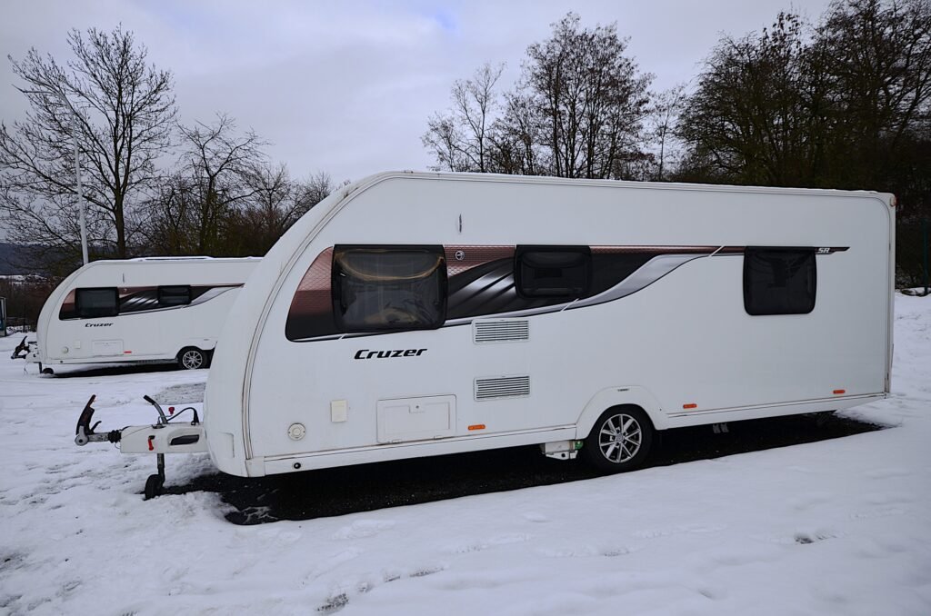 Karavan Cruzer parkovaný na sněhu, ideální pro dobrodružné výlety a pohodlný odpočinek.