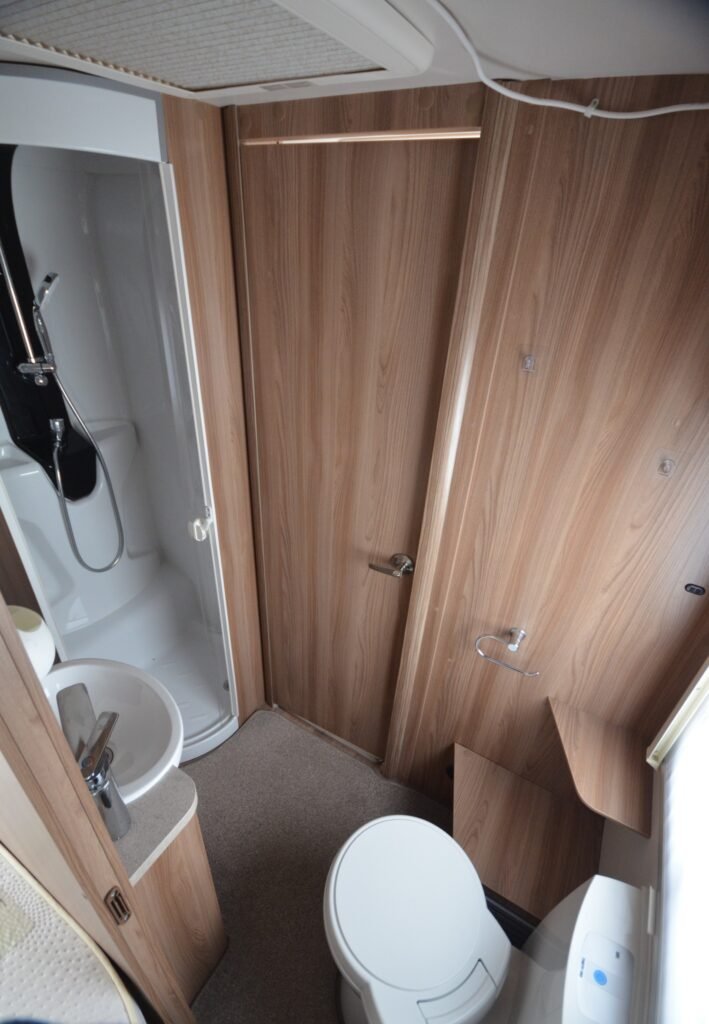 Koupelna obytného auta, moderní interiér, sprcha, toaleta a umyvadlo v elegantním designu. Ideální pro pohodlné cestování.