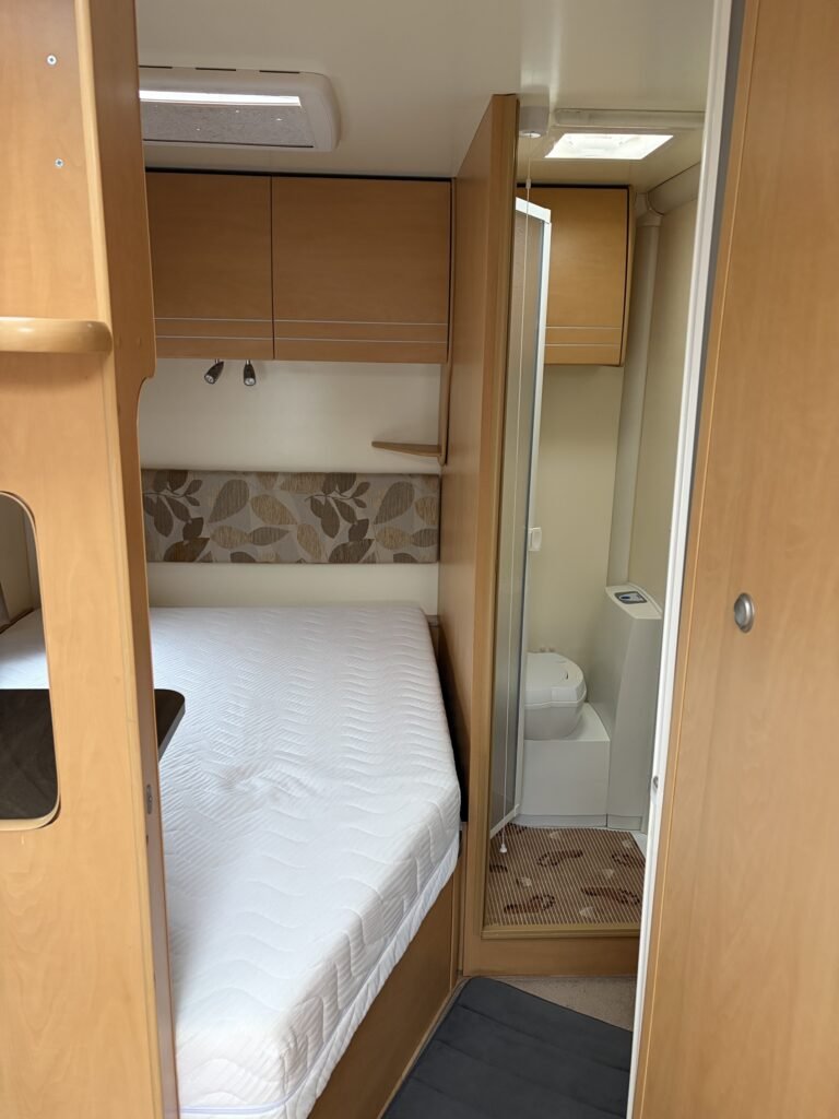Interiér karavanu s ložnicí a koupelnou. Moderní a pohodlný prostor pro cestování.