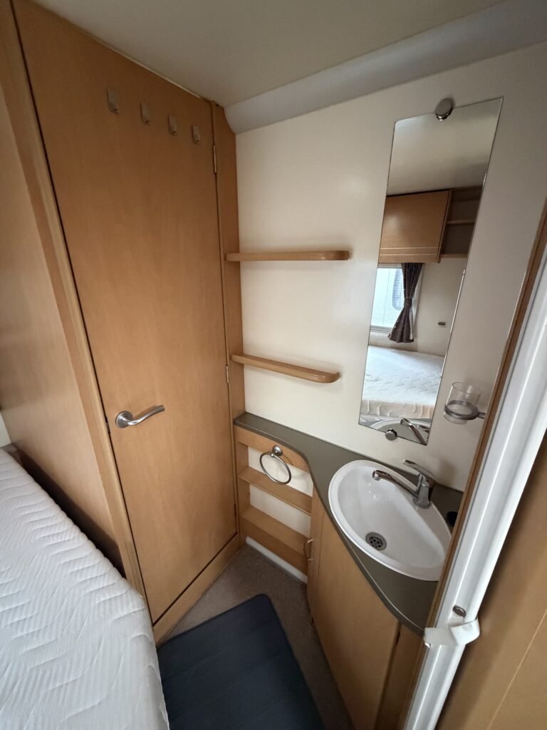 Koupelna v karavanu, úložné prostory, umyvadlo a zrcadlo. Ideální pro pohodlné cestování a kempování.