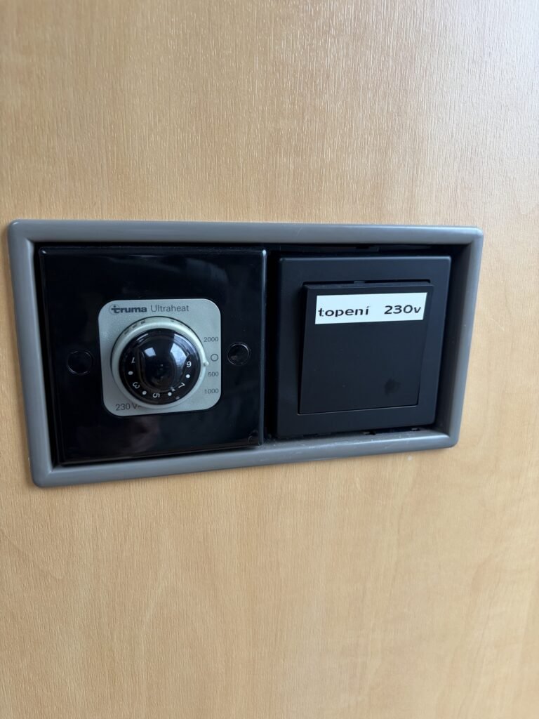 Obrázek ukazuje ovládání topení v obytném voze. Značka a model nejsou uvedeny.