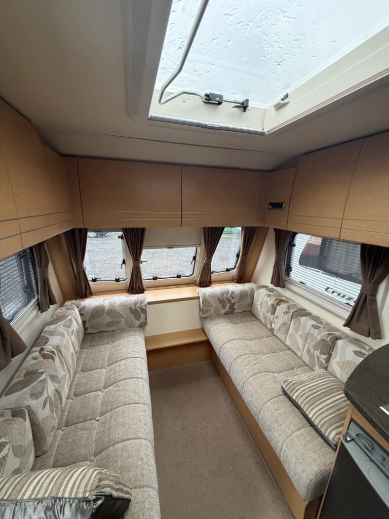 Interiér karavanu s pohodlnými sedacími úpravami a velkým oknem pro přirozené světlo.