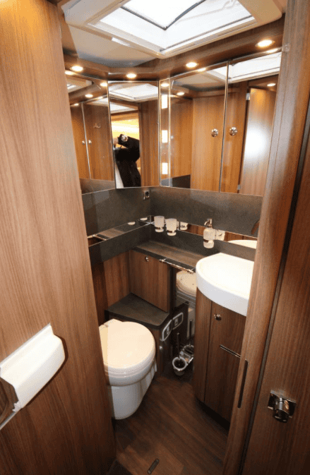 Obrázek interiéru obytného auta s moderním koupelnovým prostorem a dřevěnými obklady. Komfort a elegance.