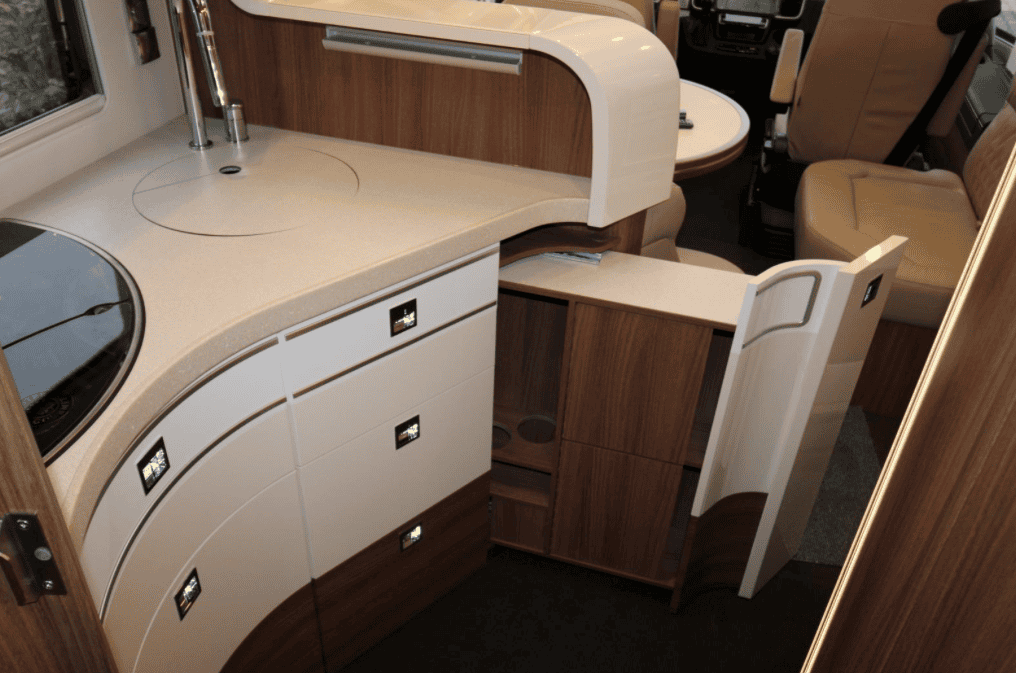 Interiér obytného auta s moderní kuchyní a pohodlným sezením. Elegantní design a funkčnost.