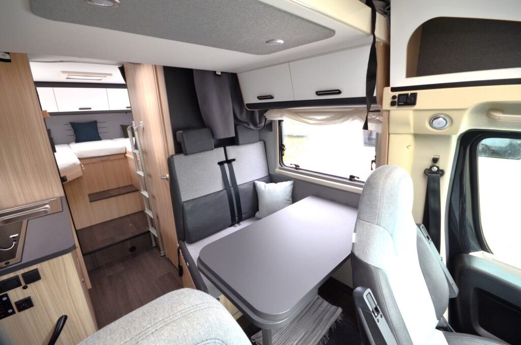 Interiér obytného auta, moderní design, pohodlné posezení a ložnice. Ideální pro cestování a relaxaci.