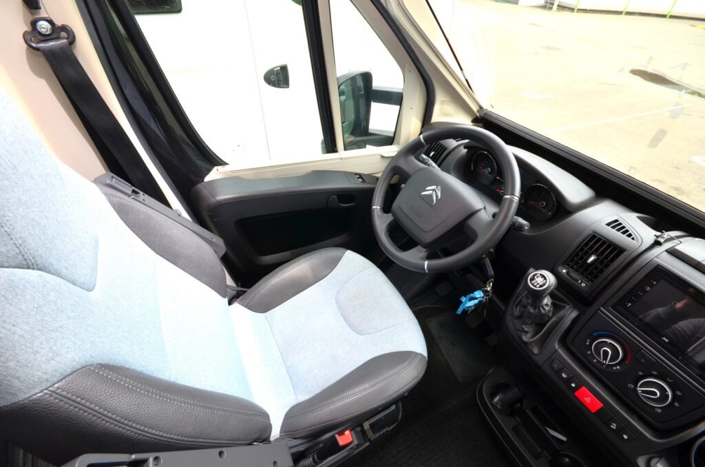 Interiér obytného auta s pohodlným sedadlem a moderním ovládáním, ideální pro cestování.