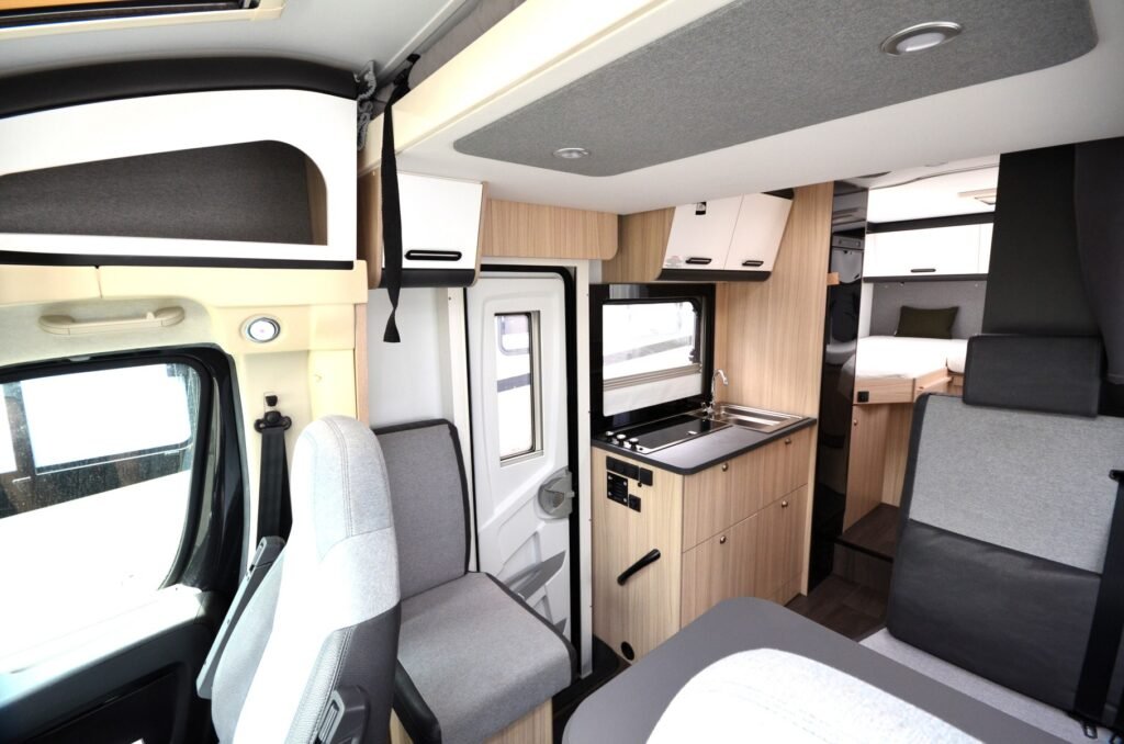 Interiér moderního obytného auta s kuchyní a pohodlnými sedadly. Ideální pro cestování a kempování.