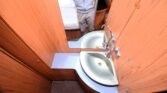 Obrázek interiéru karavanu s dvoulavou umyvadlovou částí a dřevěným obložením. Komfortní a praktický prostor.