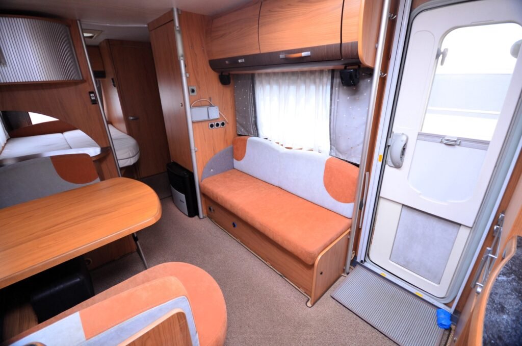 Interiér karavanu s dřevěnými prvky a pohodlným posezením. Ideální pro kempování a dobrodružství na cestách.