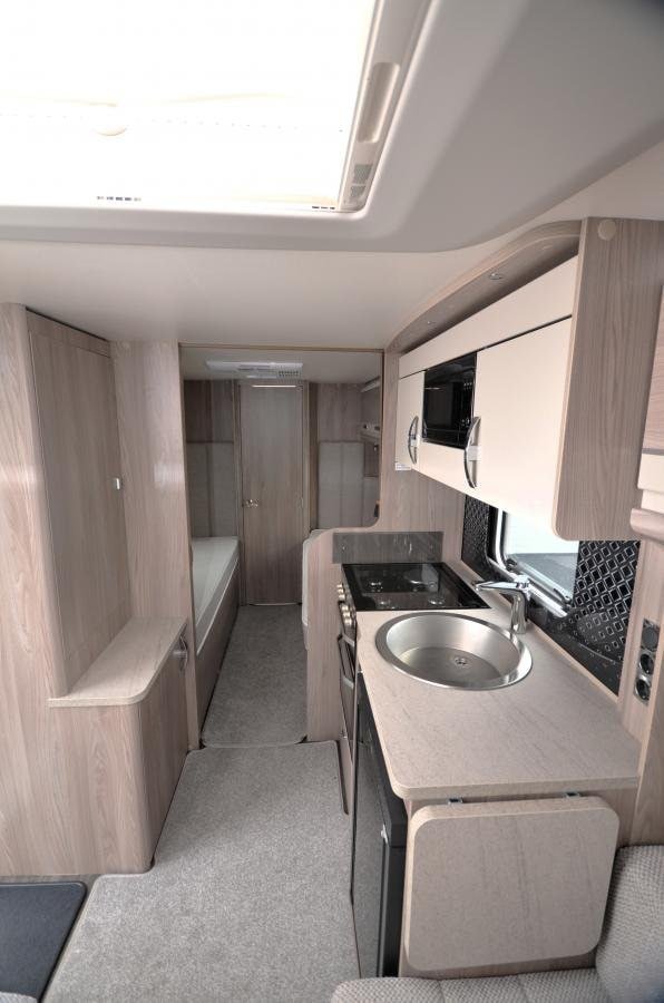 Moderní interiér obytného vozu s kuchyňskou linkou a pohodlným uspořádáním. Ideální pro cestování a kempování.