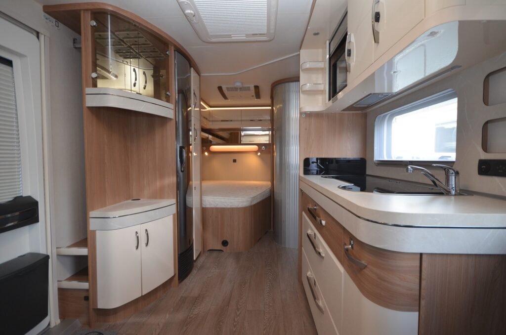 Interiér karavanu s moderní kuchyní a komfortním obývacím prostorem. Ideální pro dobrodružství na cestách.