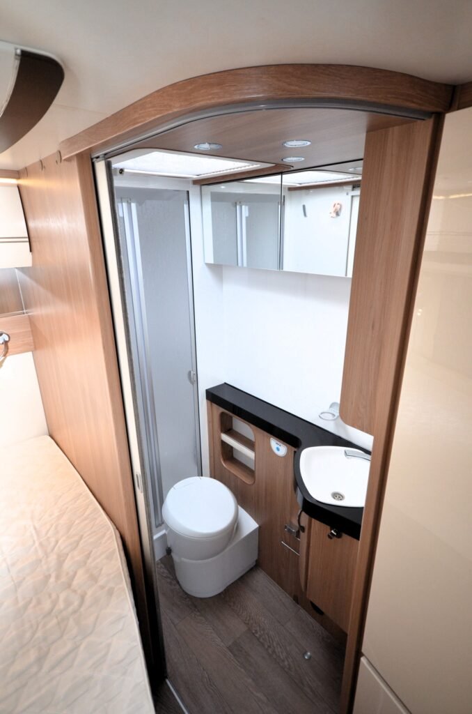 Interiér obytného vozu s koupelnou, vanou a úložným prostorem. Moderní a praktický design pro pohodlné cestování.