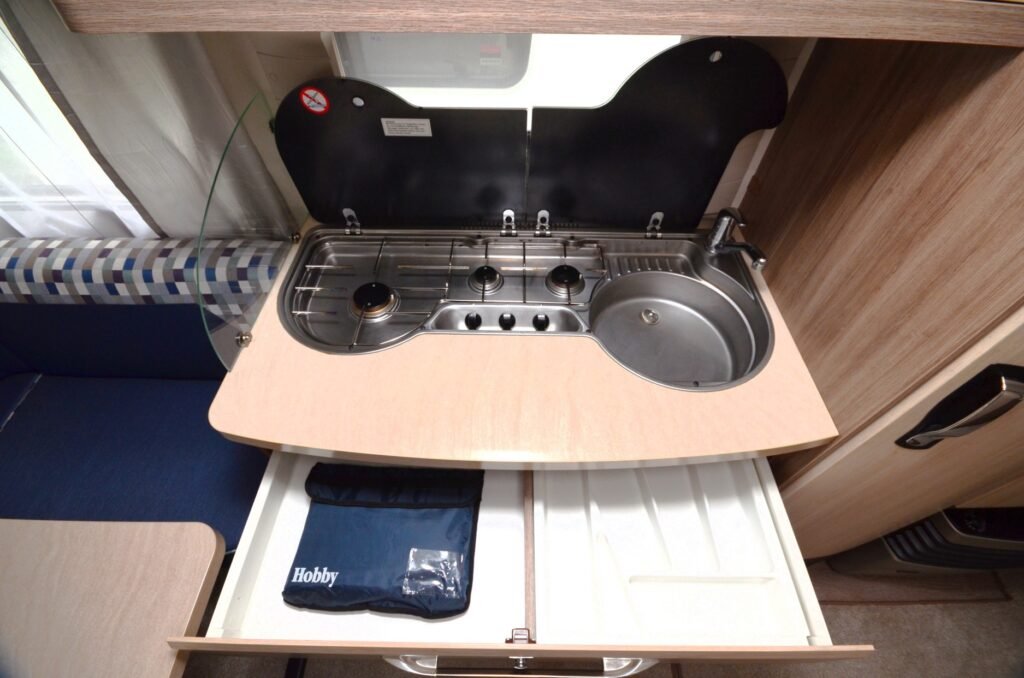 Kuchyňka v karavanu Hobby s dřezem a sporákem pro pohodlné vaření na cestách.