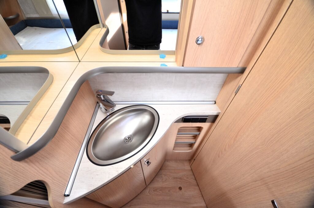 Obrázek interiéru obytného vozu s moderním umyvadlem a dřezem v příjemném designu.