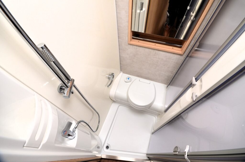 Obrázek zobrazuje sprchu a toaletu v obytném autě. Moderní a praktický design pro pohodlí na cestách.