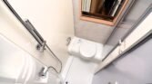 Obrázek zobrazuje sprchu a toaletu v obytném autě. Moderní a praktický design pro pohodlí na cestách.