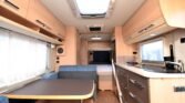 Interiér karavanu s moderním designem, kuchyňkou a obytným prostorem pro pohodlné cestování.