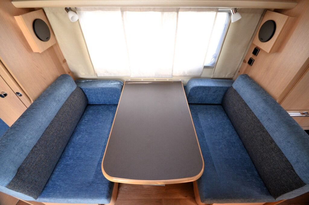 Interiér karavanu s pohodlnými sedačkami a stolem, ideální pro relaxaci a společné chvíle.