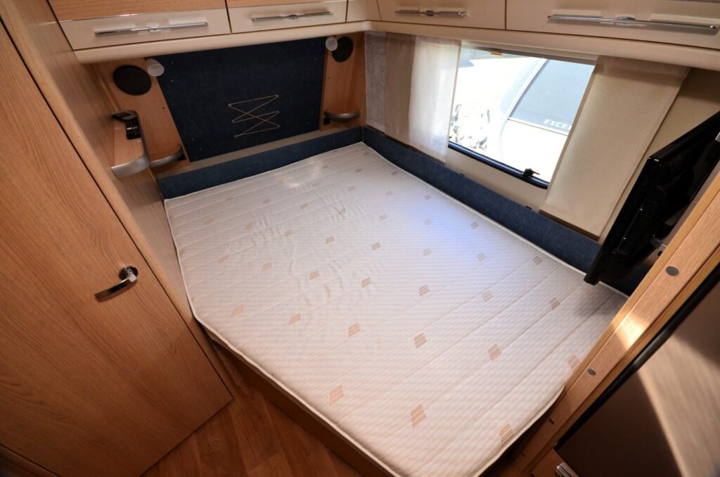 Interiér obytného auta s pohodlným lůžkem a úložnými prostorem. Ideální pro vaše cestování.