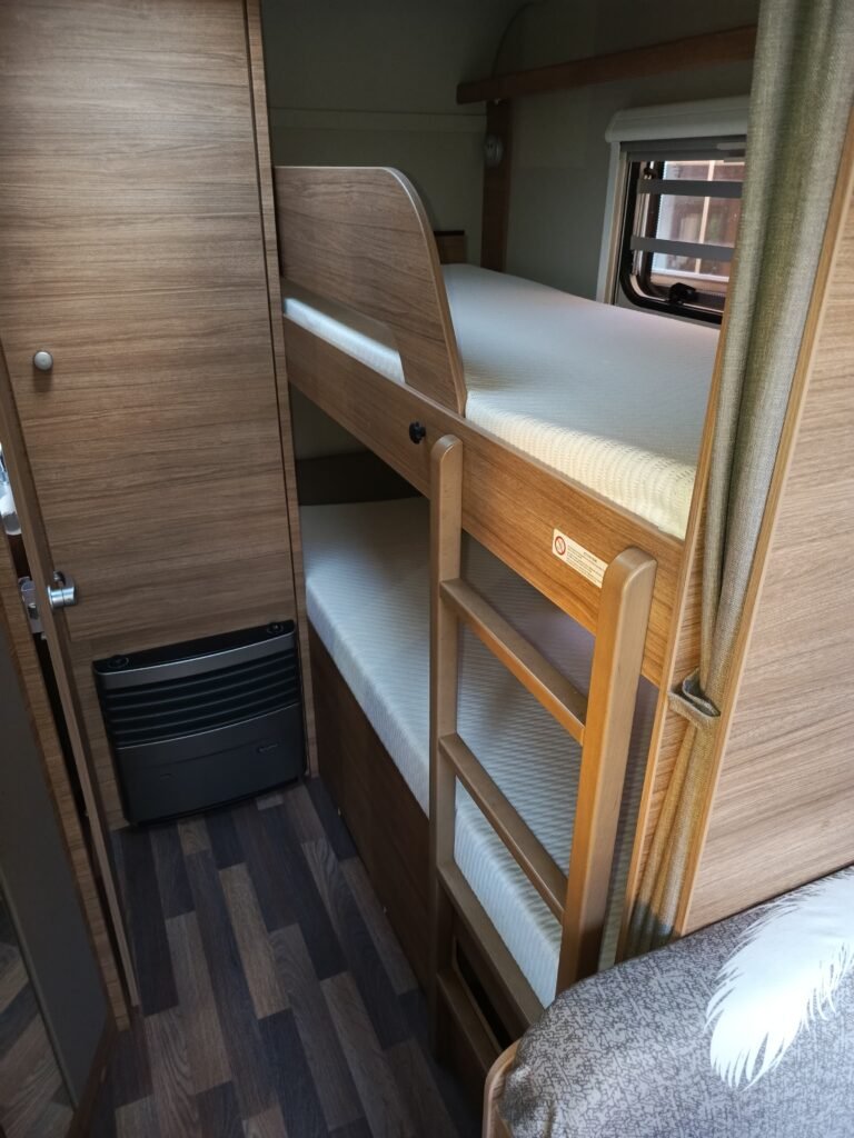 Obrázek zobrazuje interiér obytného vozu s palandou a prostorovým uspořádáním. Komfortní a praktické řešení pro rodiny.