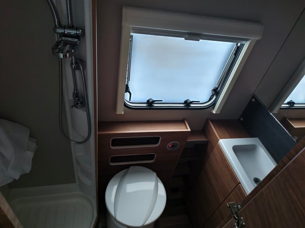 Interiér karavanu, moderní vybavení včetně sprchy a toalety. Ideální pro pohodlné cestování.