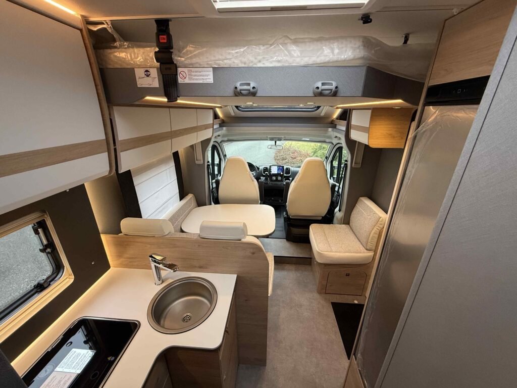 Moderní interiér obytného auta s kuchyňským koutem a pohodlným sezením. Ideální pro dobrodružství na cestách.