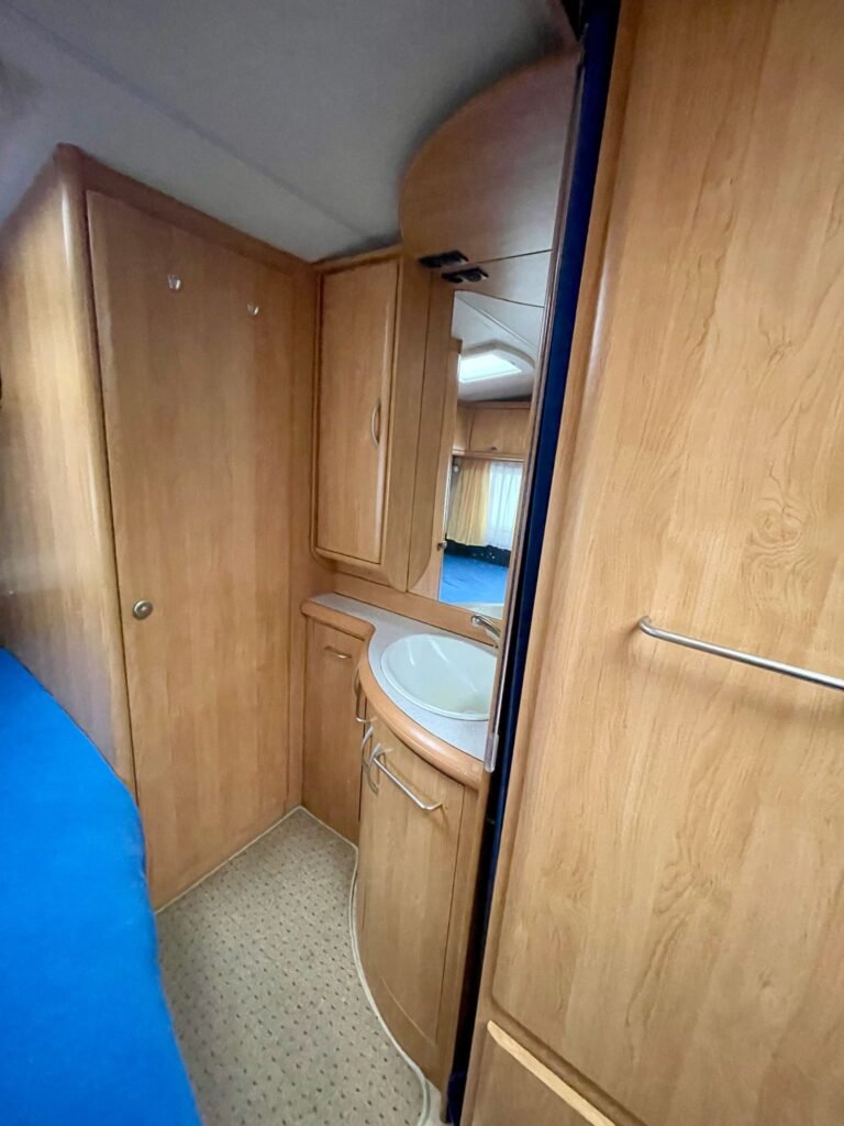 Interiér karavanu, dřevěný dům s umyvadlem a úložnými prostory. Ideální pro pohodlné cestování.