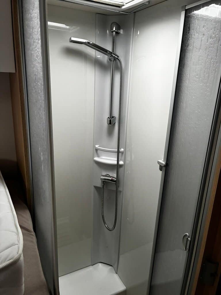 Obrázek zobrazuje sprchový kout, ideální pro komfortní obytné auto. Udržuje rozměrný prostor.