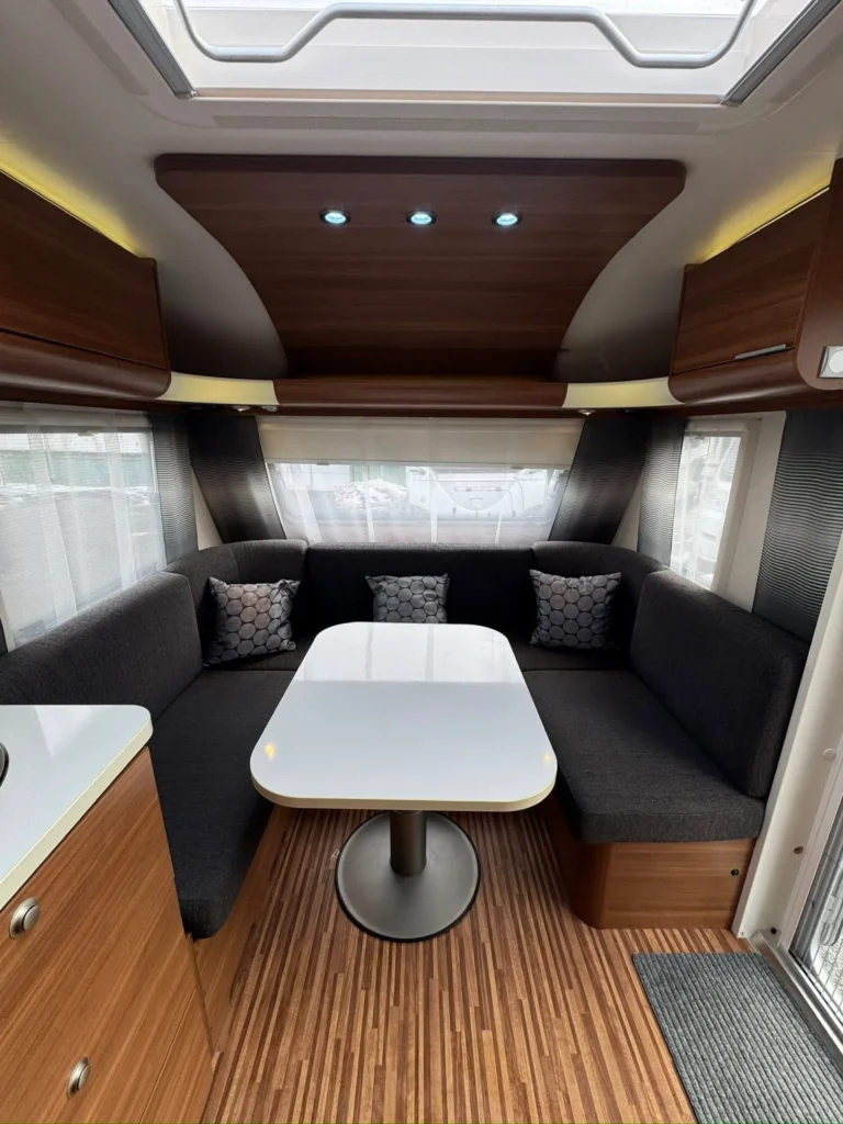 Interiér karavanu s pohodlným sezením a stolem, ideální pro relaxaci a společné chvíle.
