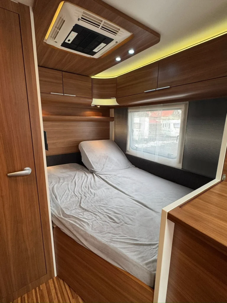 Interiér karavanu s ložnicí a skříňkami. Elegantní dřevěný design pro pohodlné cestování.
