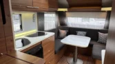 Interiér moderního karavanu s prostornou kuchyní a pohodlným sezením. Ideální pro pohodlné cestování a relaxaci.
