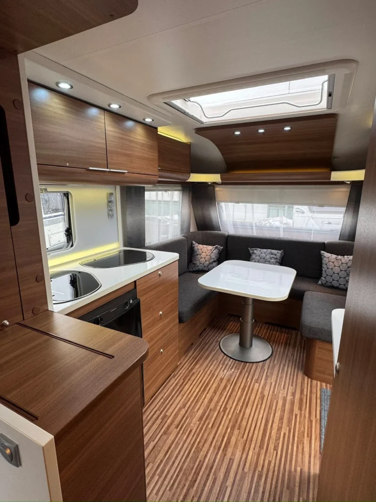 Interiér moderního karavanu s prostornou kuchyní a pohodlným sezením. Ideální pro pohodlné cestování a relaxaci.