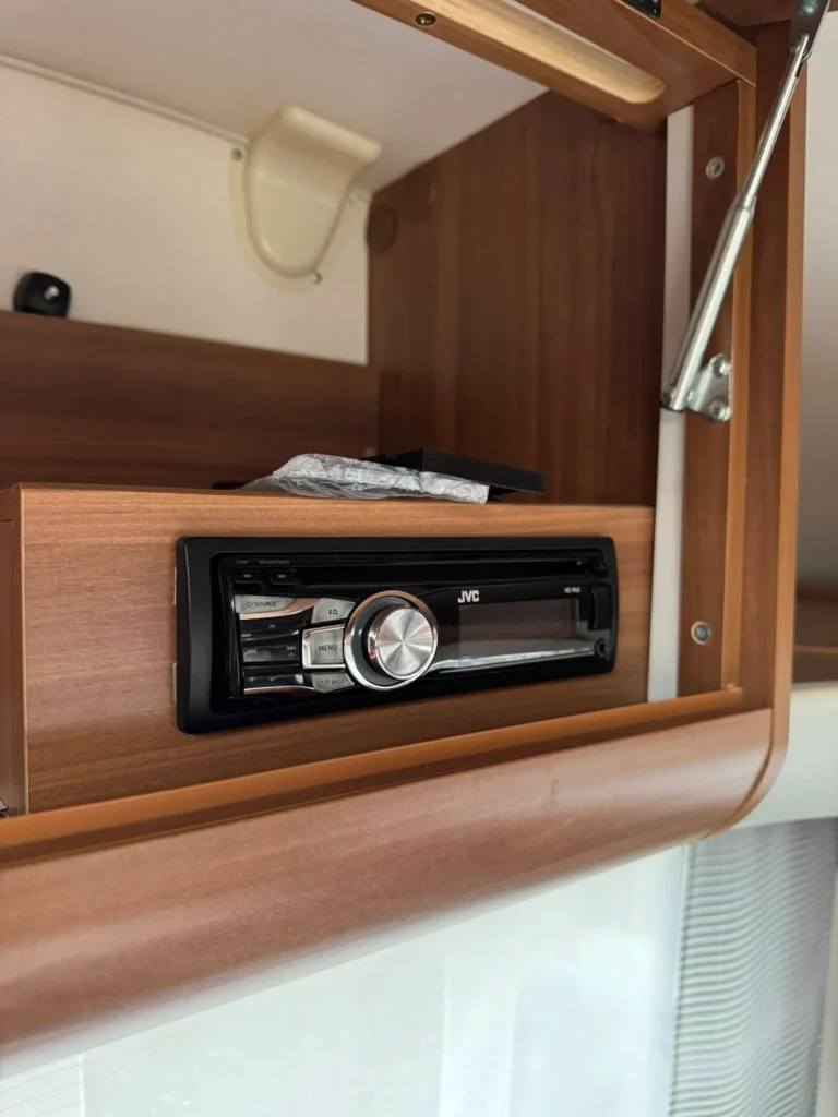 Obrázek zobrazuje rádio značky JVC v útrobách obytného auta. Ideální pro pohodlné cestování.