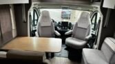 Interiér obytného auta LMC s pohodlnými sedadly a stolem pro odpočinek. Ideální pro cestování a relaxaci.