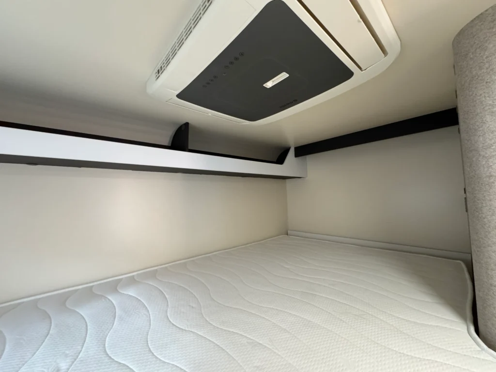 Na obrázku je interiér obytného auta s klimatizací a polstrovanou postelí, ideální pro komfortní cestování.