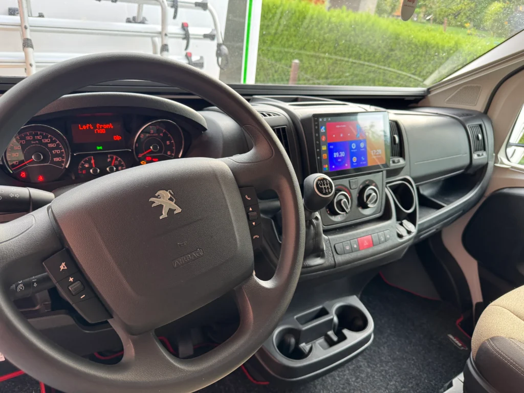 Interiér obytného auta Peugeot s moderním multimediálním systémem a komfortním ovládáním.