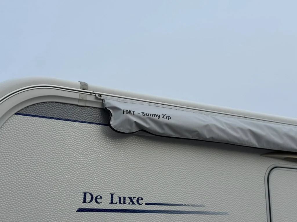 Na obrázku je karavan De Luxe s markýzou FMT - Sunny Zip. Ideální pro relaxaci na cestách.